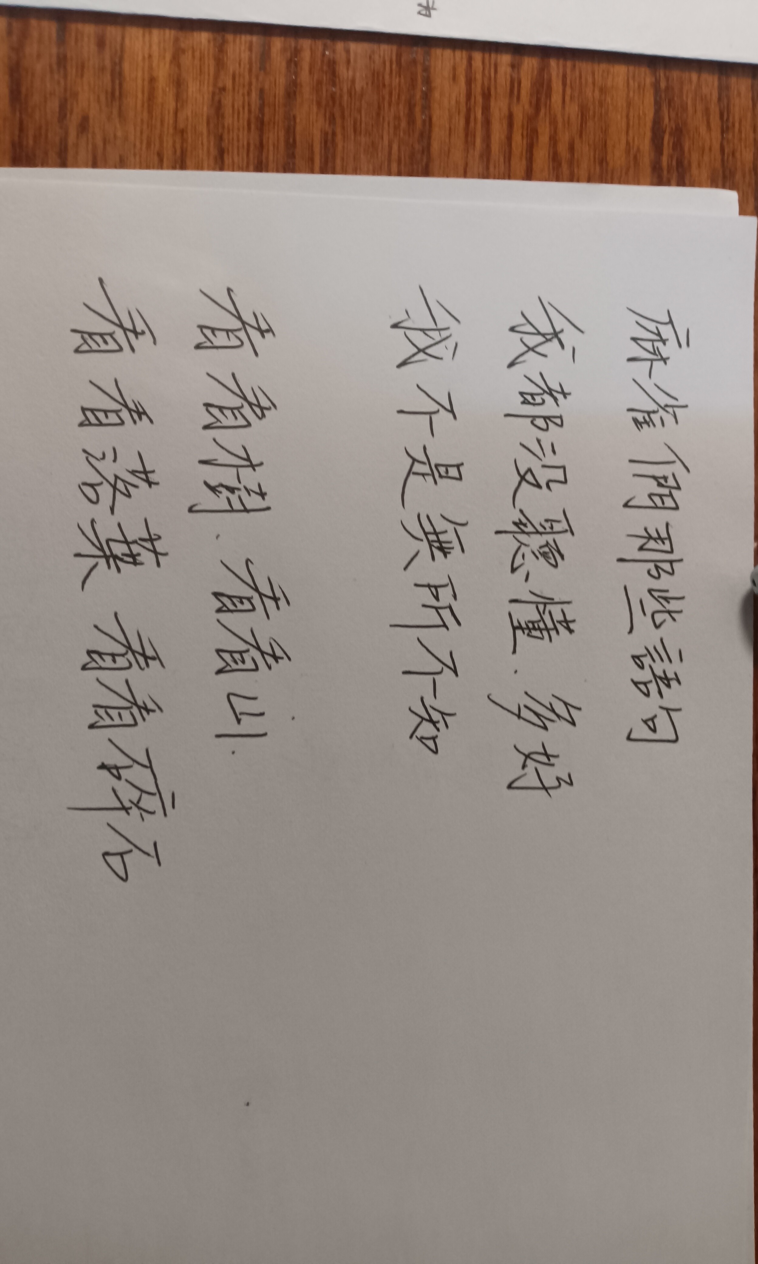 The image shows handwritten Chinese characters on a piece of paper, possibly a poem or a practice sheet. (Captioned by AI)