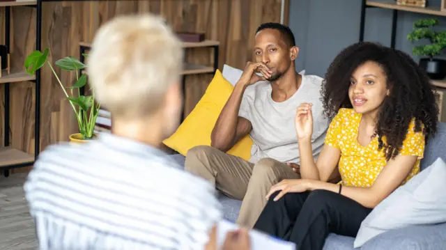 两个人坐在沙发上交谈,面前似乎有一位治疗师